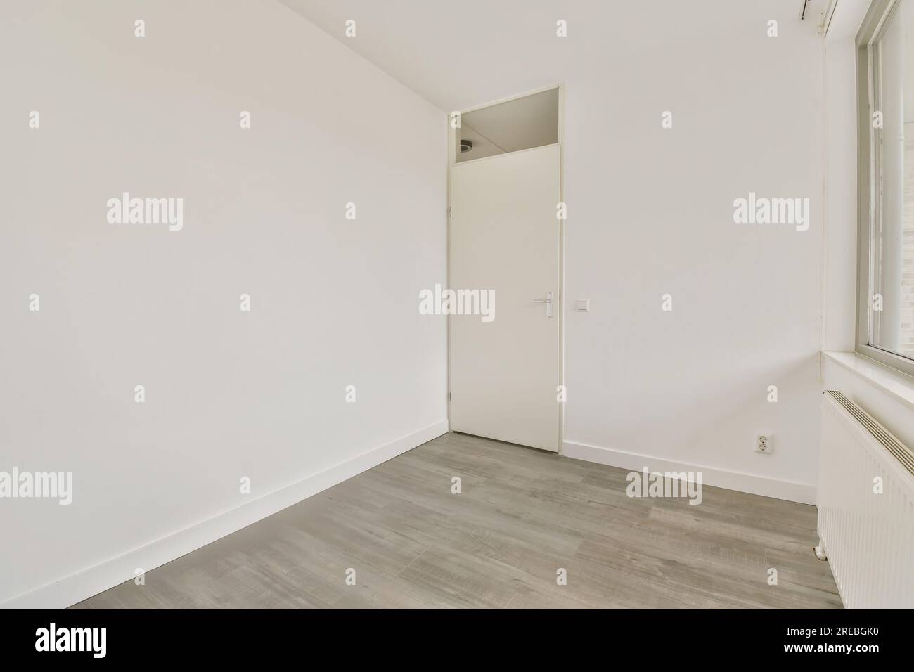 an empty room with wood floors and white walls, there is a door leading ...