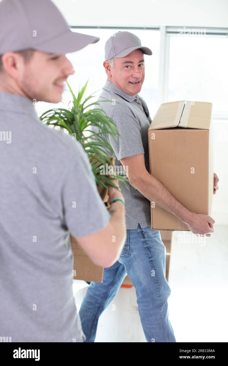 two cheerful removals men carrying belongings Stock Photo