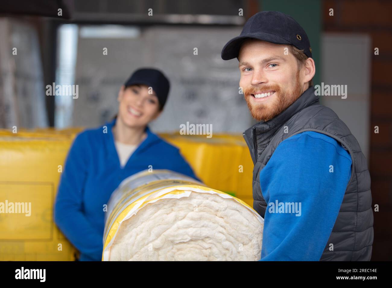 two workers carry roll of insulation Stock Photo