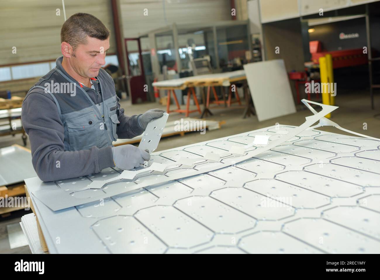 factory man worker holding steel sheet and removing metal burrs Stock