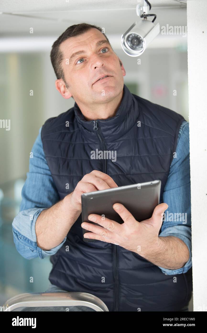 man with digital tablet inspecting surveillance camera Stock Photo