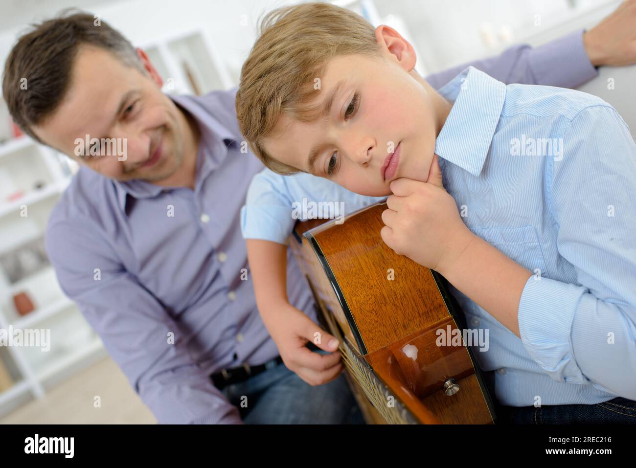 Child learning guitar, holding his chin Stock Photo Alamy