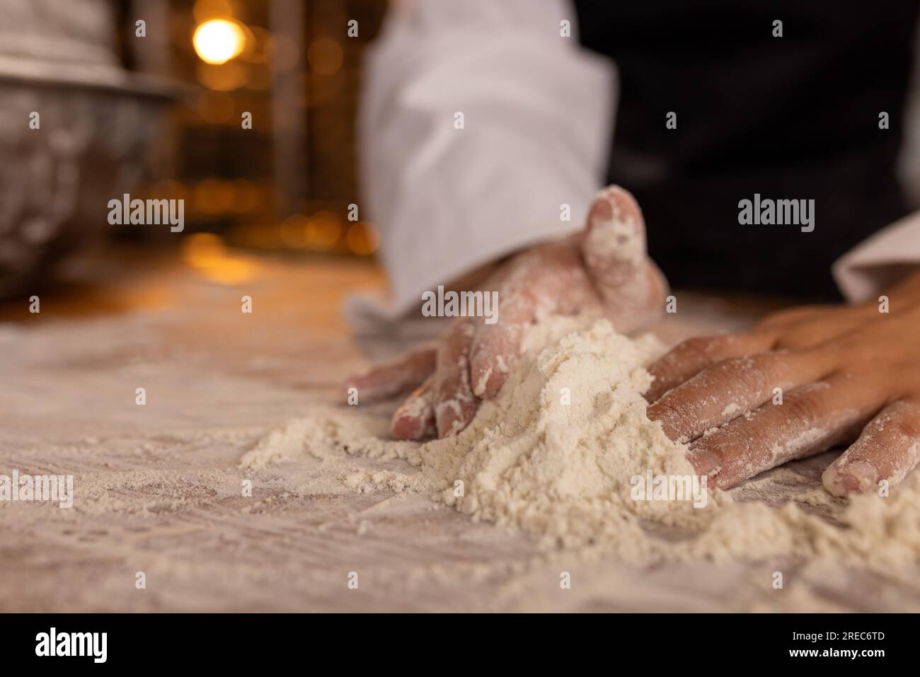 Asian female baker working in bakery kitchen, kneading dough, copy space Stock Photo