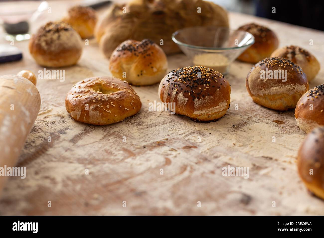 Close up of roller and fresh rolls with seeds on countertop with flour in bakery kitchen, copy space Stock Photo