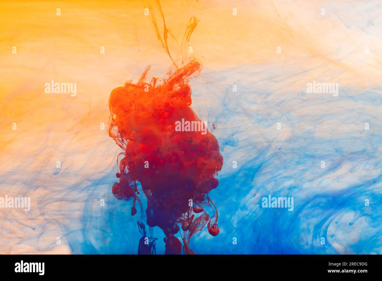 Close up of orange, yellow and blue ink in water with copy space background Stock Photo