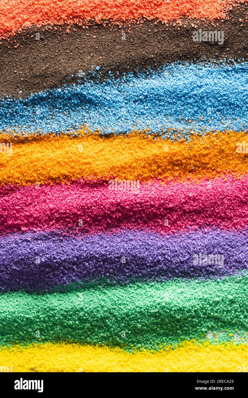 Close up of stripes of rainbow coloured sand and copy space background
