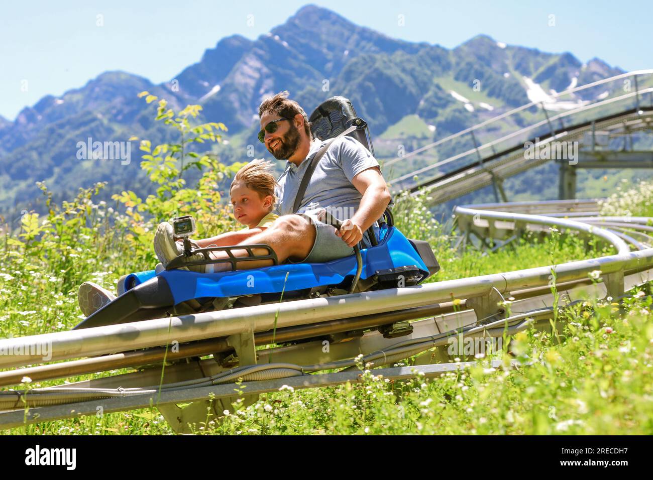 father and child having ride on summer toboggan called Rodelbahn