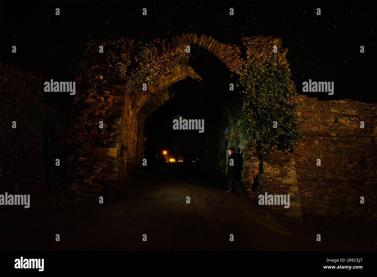 A night shot of a man standing in the entrance to Launceston Castle in Launceston, UK Stock Photo