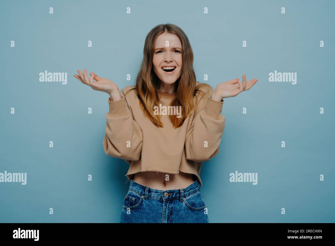 Studio shot of attractive amazed teenage girl in stylish casual outfit, cannot believe her eyes, shrugging shoulders with a surprised face expression, Stock Photo