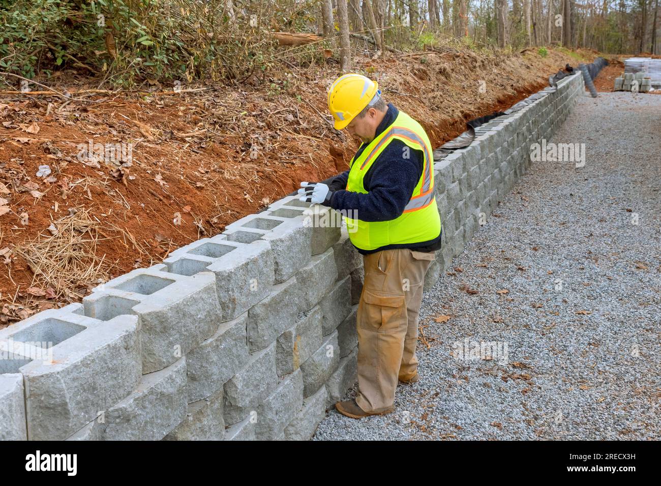 Construction worker, am mounting retaining wall with concrete blocks to