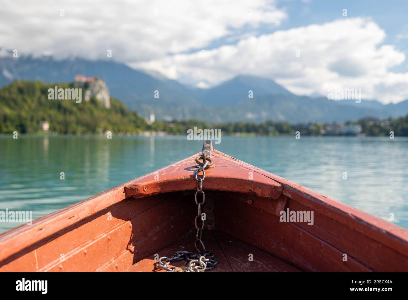 The bow of a red rowing boat on Lake Bled in Slovenia. In the blur you can see Bled Castle Stock