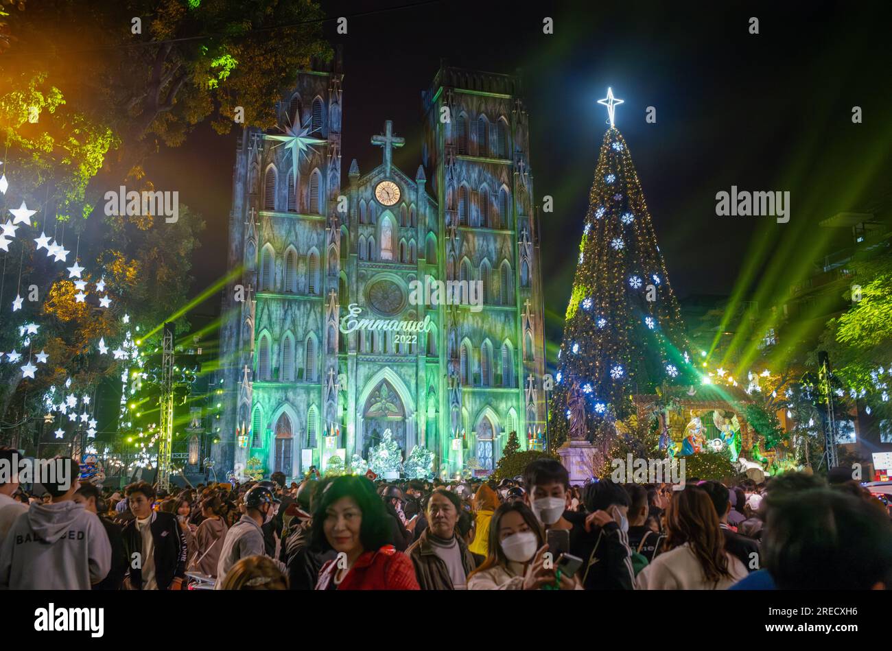 Crowds of Vietnamese people gather next to the dramatically illuminated St Joseph's Cathedral and its Christmas Tree at CHristmas time in Hanoi, Vietn Stock Photo
