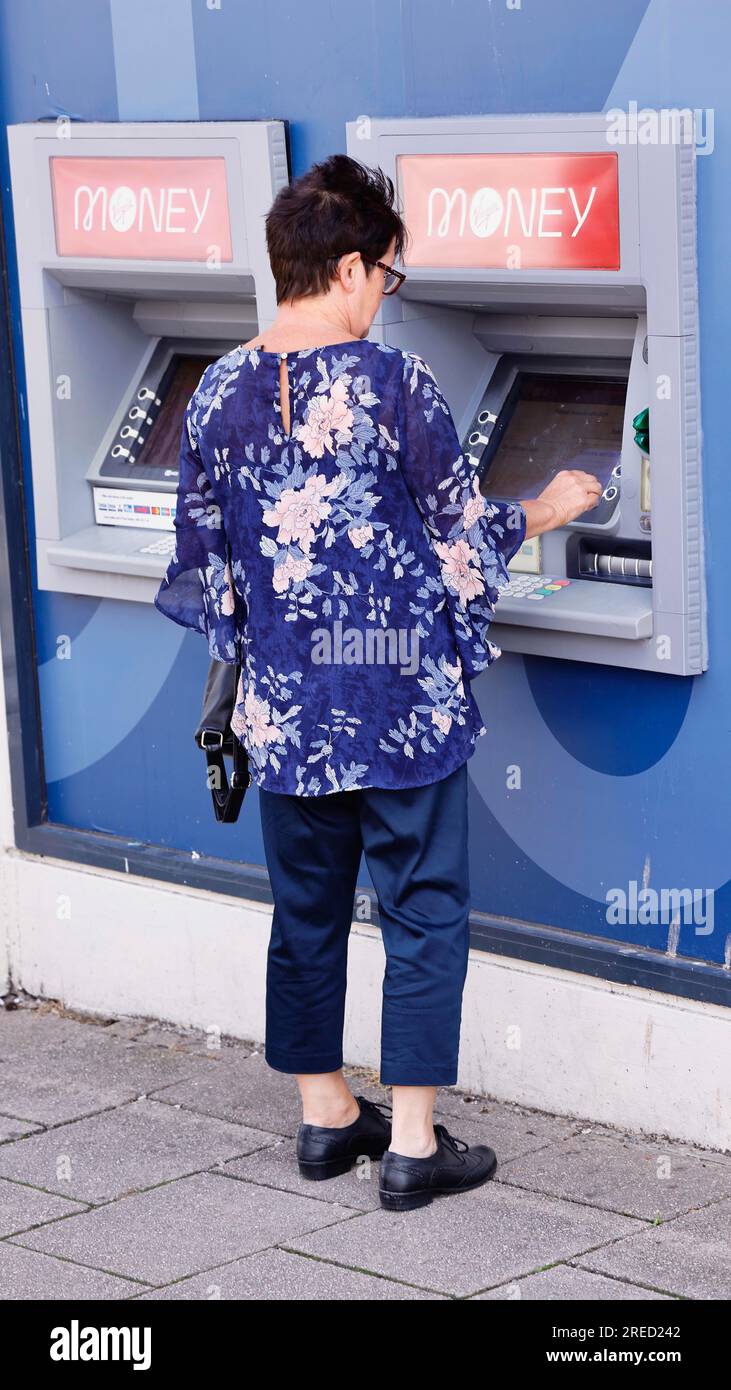 Finance, Banks, Money, Woman using ATM in high street to withdraw cash. Stock Photo