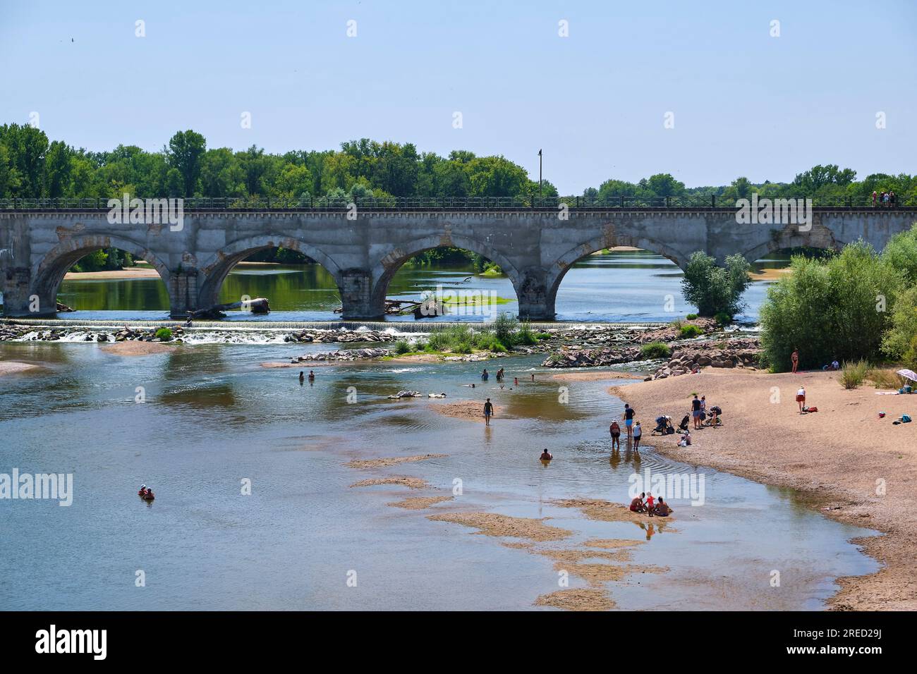 Beach on the banks of the Allier River at the bottom of the Guetin navigable aqueduct in Cuffy (central France). Tourists enjoying the coolness of the Stock Photo