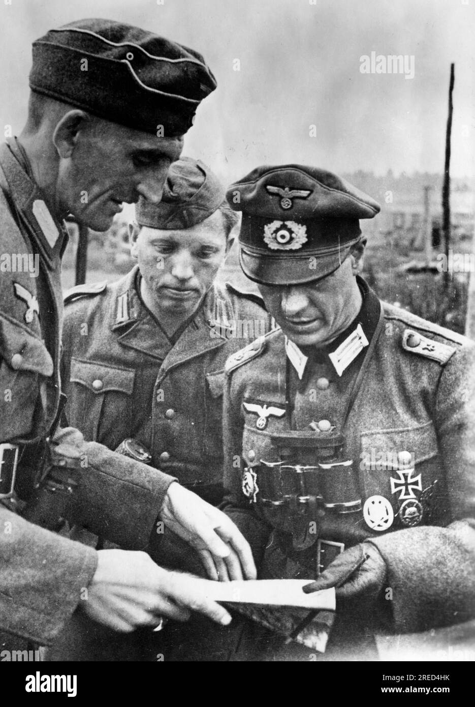 A German Wehrmacht official (left) talking with a Wehrmacht officer. In the middle, the member of a national unit formed from Russian volunteers, which is to be used to fight a group of partisans. Near Chelnovya. Photo: Götze. [automated translation] Stock Photo