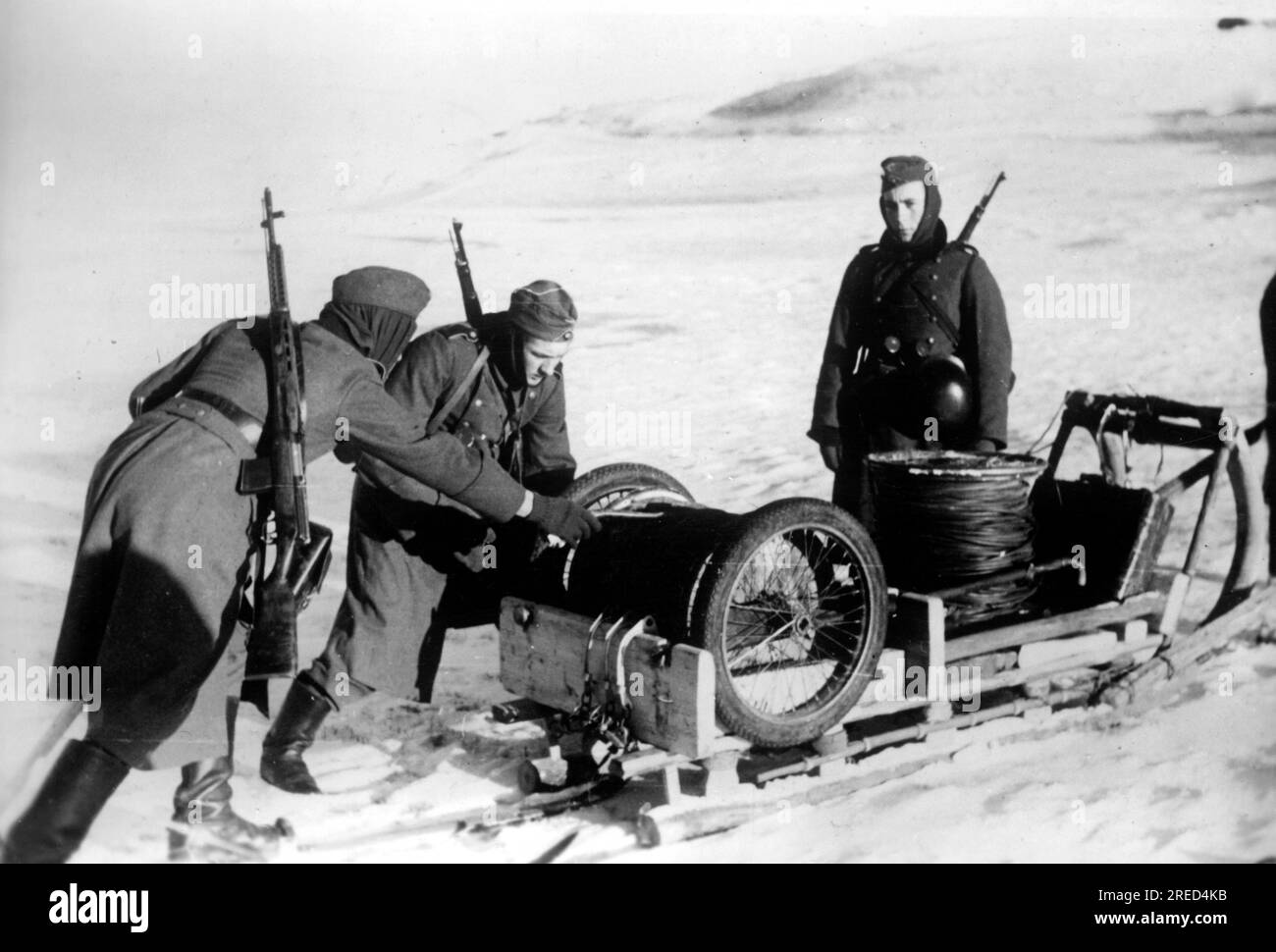 German soldiers laying telephone cable with the help of a sledge near Molwotizi in the northern section of the Eastern Front. The soldier on the left carries a Russian SWT 40 rifle over his shoulder. Photo: Fenske. [automated translation] Stock Photo