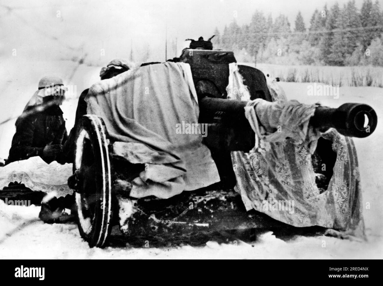 German soldiers with a 5cm Pak 38 on the Eastern Front. The gun is camouflaged with cloths from the household, including a curtain. In the background a Panzer III. photo: Qual. [automated translation] Stock Photo