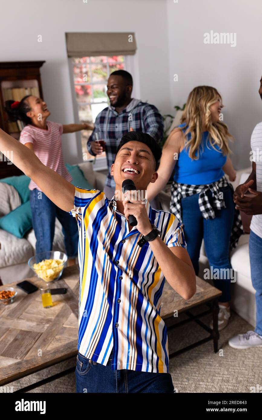 Happy diverse friends dancing and karaoke singing with microphone at