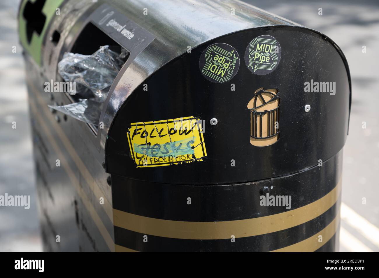 Municipal litter bin with fly posted stickers on a street in central