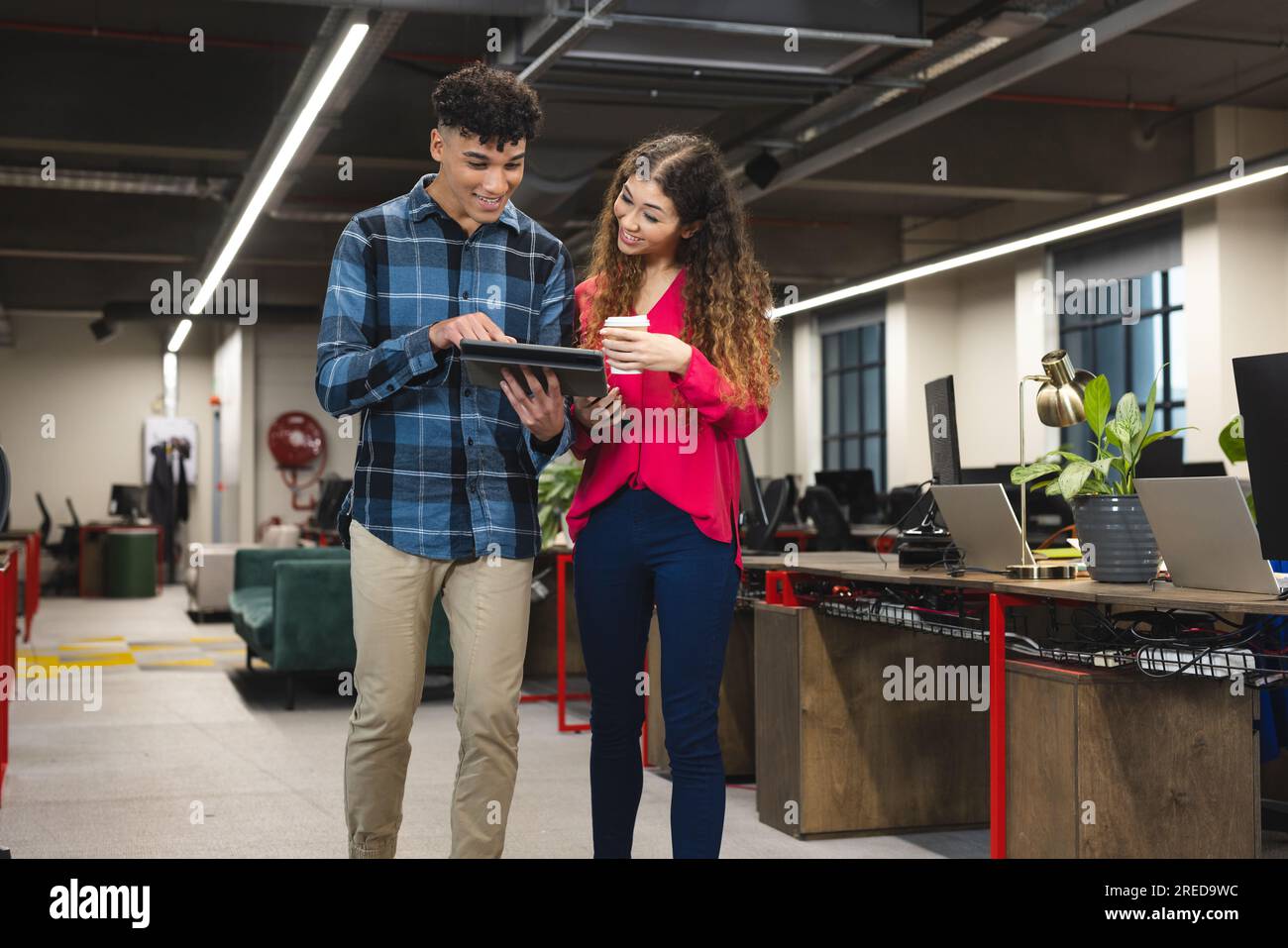 Happy diverse male and female colleagues using tablet and talking ...