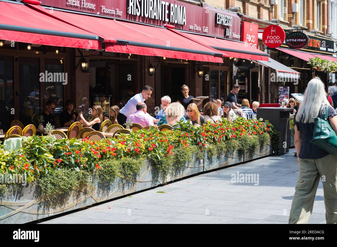 People dining al fresco at the pavement terrace outside Ristorante Roma Italian restaurant on a sunny summer day. Irving Street, London, England, UK Stock Photo