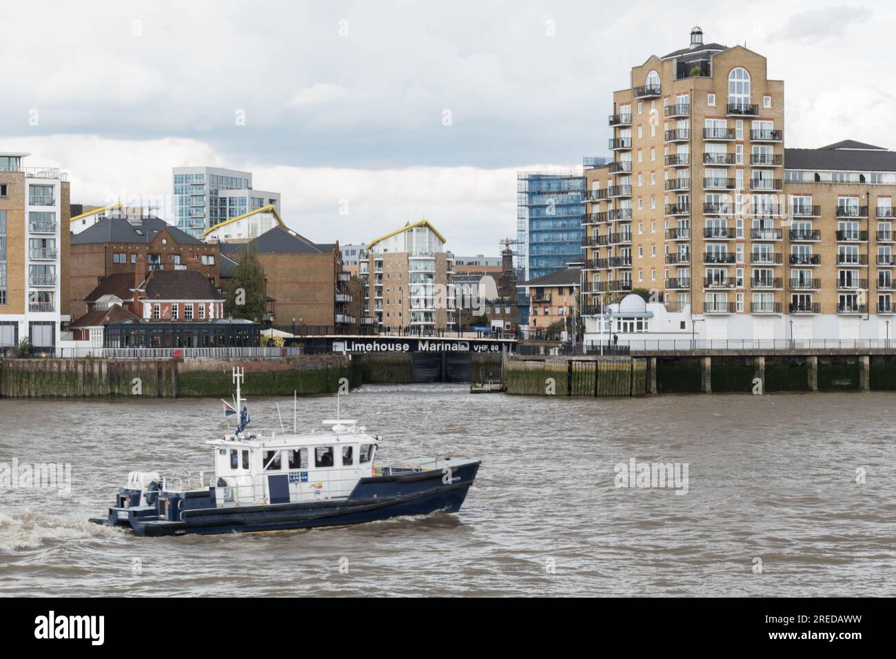 A Port of London Authority launch passing in front of the entrance to Limehouse Marina on the River Thames at Limehouse, London, E1, England, U.K. Stock Photo