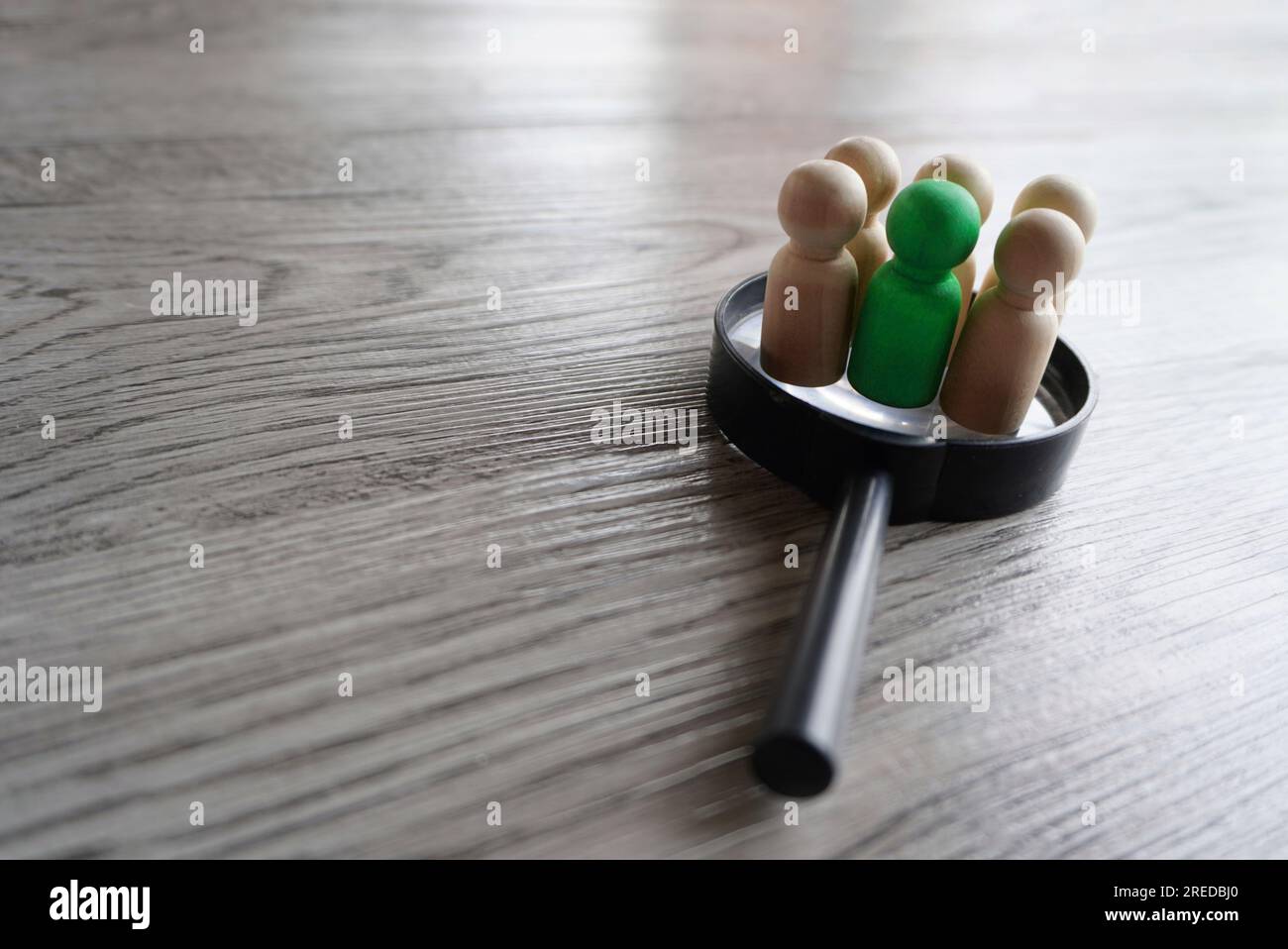 Wooden dolls on top of magnifying glass. Human resources, target market and audience, focus group concept Stock Photo