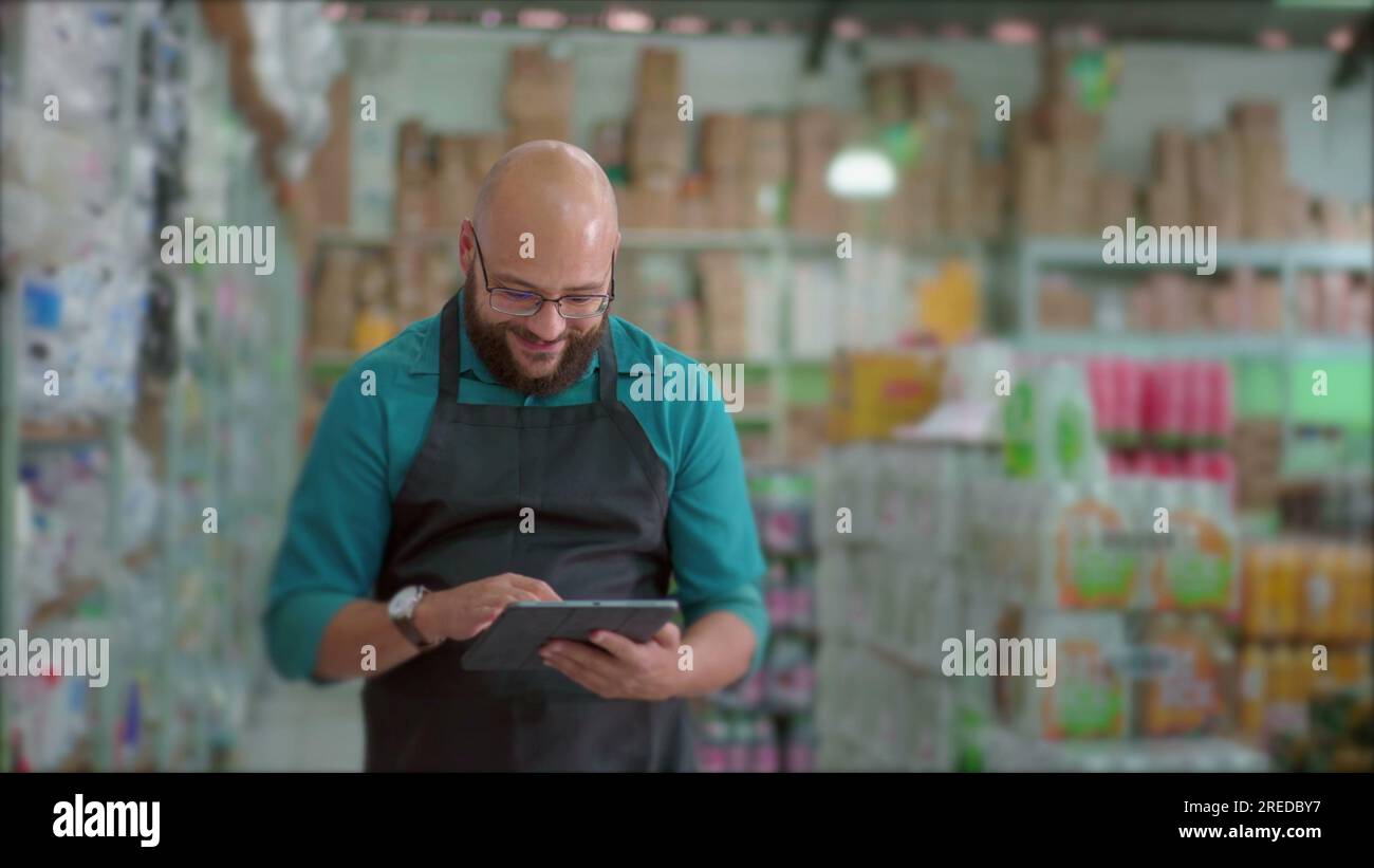 Happy employee walking in Grocery Store aisle with tablet device