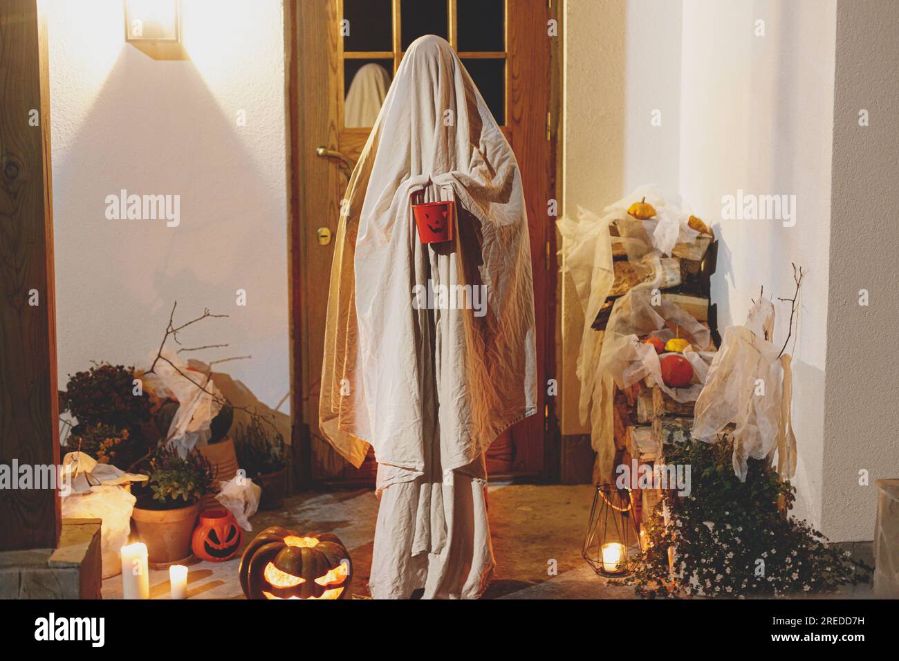 Scary ghost with halloween candy bucket and glowing Jack o lantern