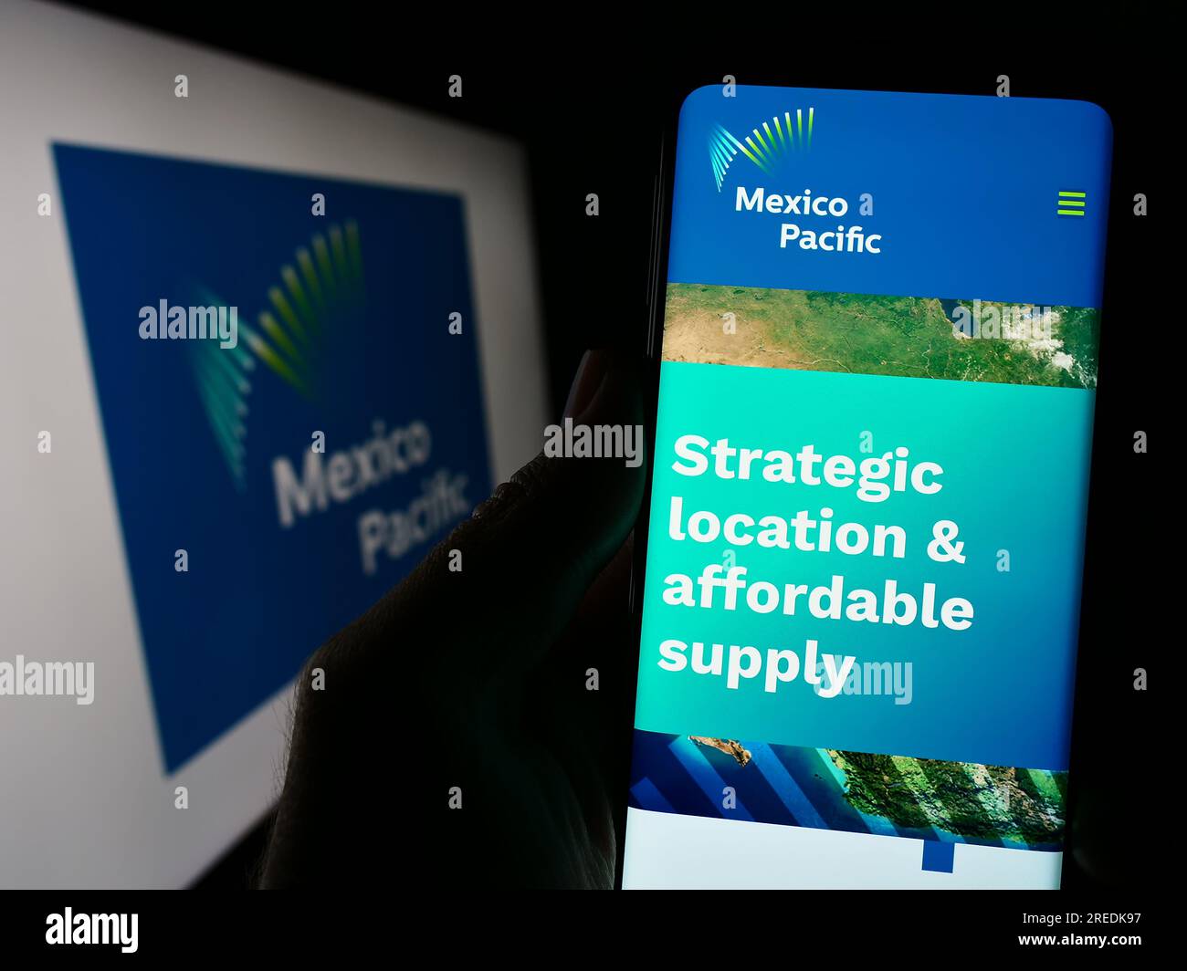 Person holding smartphone with website of company Mexico Pacific Ltd. LLC on screen in front of business logo. Focus on center of phone display. Stock Photo