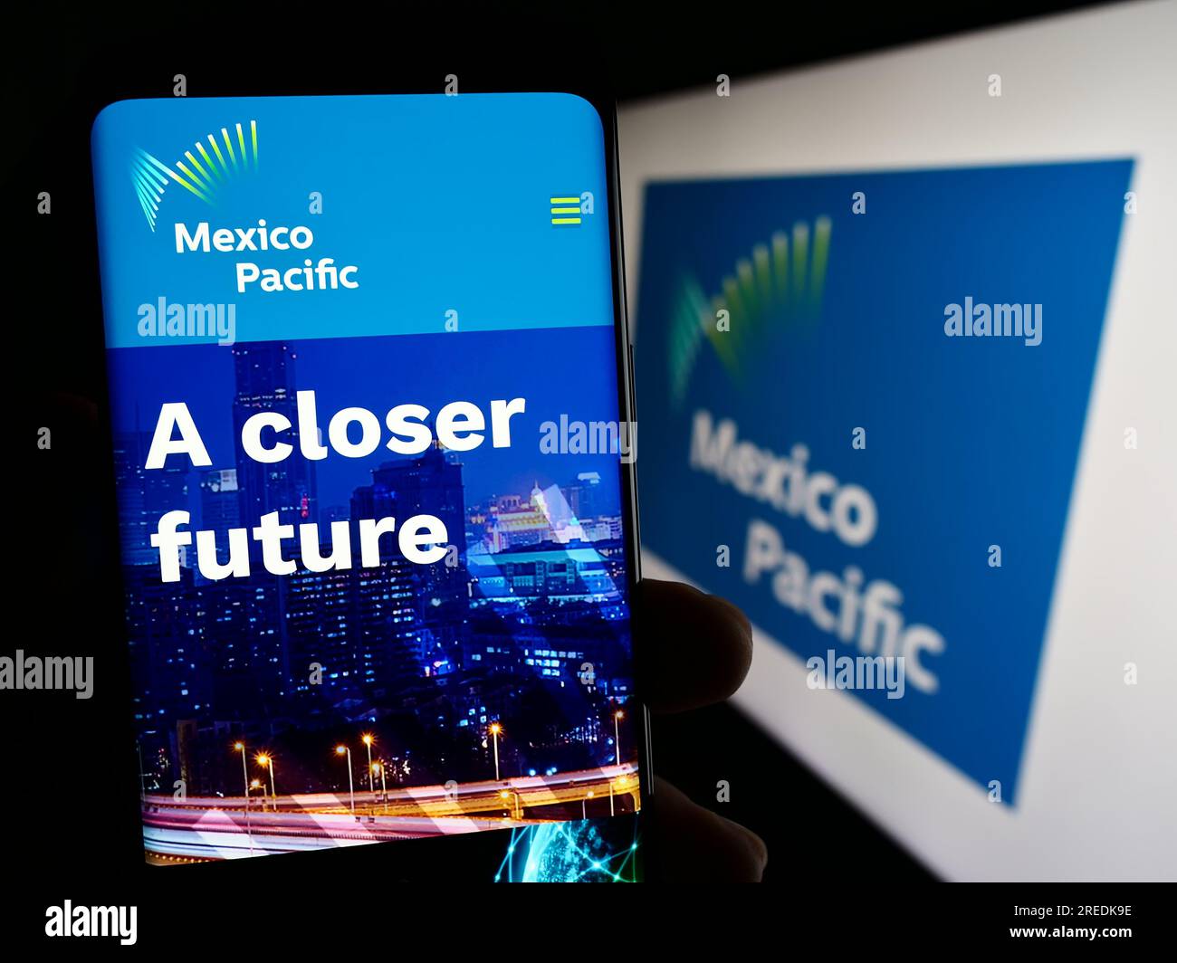 Person holding cellphone with webpage of company Mexico Pacific Ltd. LLC on screen in front of business logo. Focus on top-left of phone display. Stock Photo