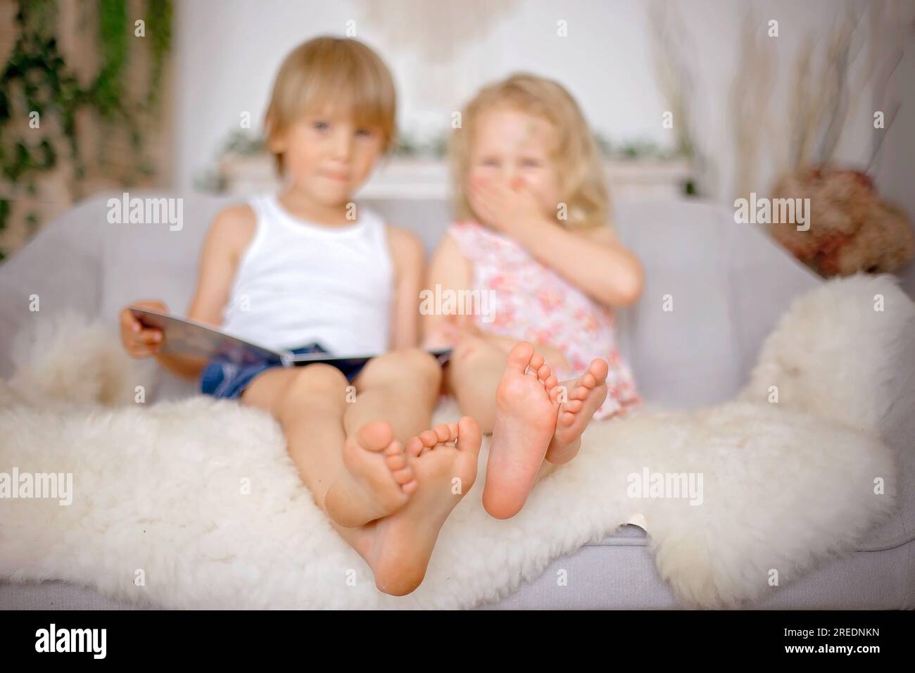 Cute sweet toddler children, tickling feet on the bed, laughing and smiling, childish mischief, happiness Stock Photo