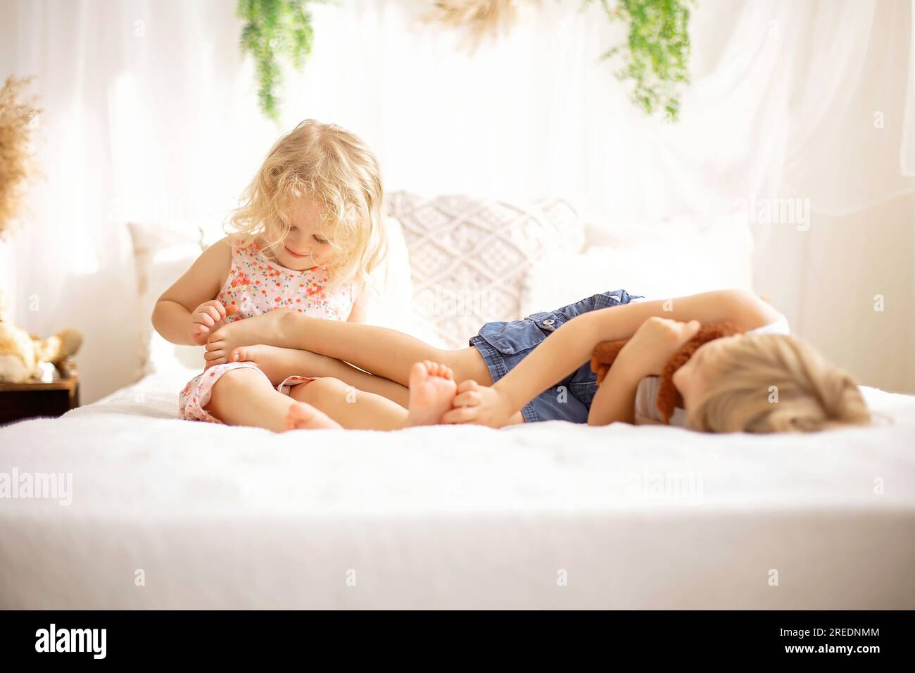 Cute sweet toddler children, tickling feet on the bed, laughing and smiling, childish mischief, happiness Stock Photo