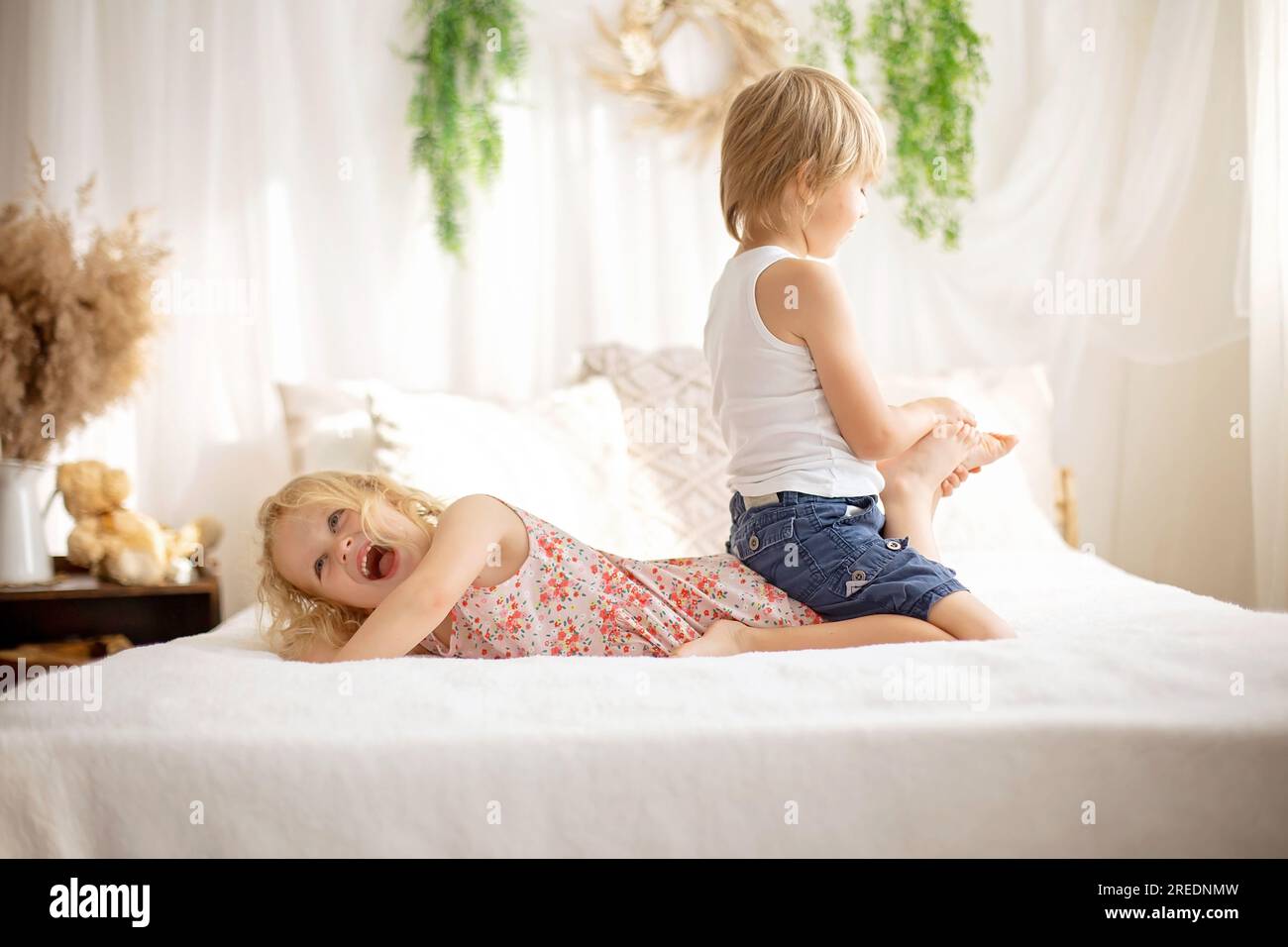 Cute sweet toddler children, tickling feet on the bed, laughing and smiling, childish mischief, happiness Stock Photo