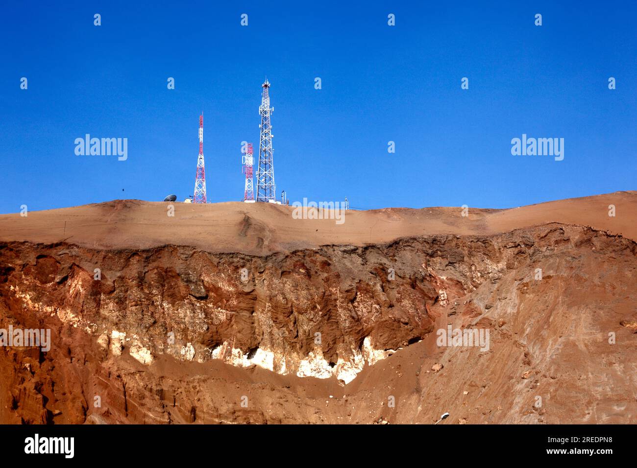 Mobile phone / radio masts and rock strata on desert hillside near the El Morro headland, near Arica, Chile Stock Photo