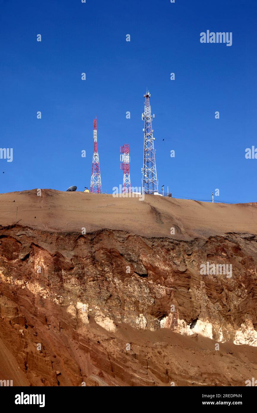 Mobile phone / radio masts and rock strata on desert hillside near the El Morro headland, near Arica, Chile Stock Photo