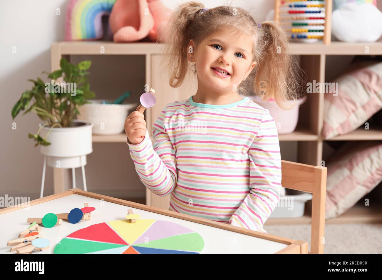 Cute little girl playing matching game with clothespins at home Stock Photo Alamy