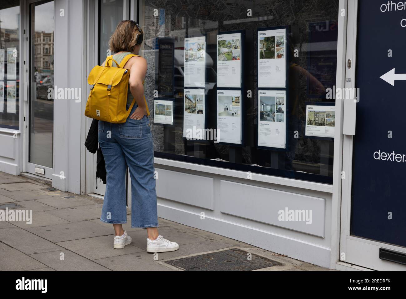 A young woman looks at rental properties in an estate agent window on Kentish Town Road, London, England, UK Stock Photo