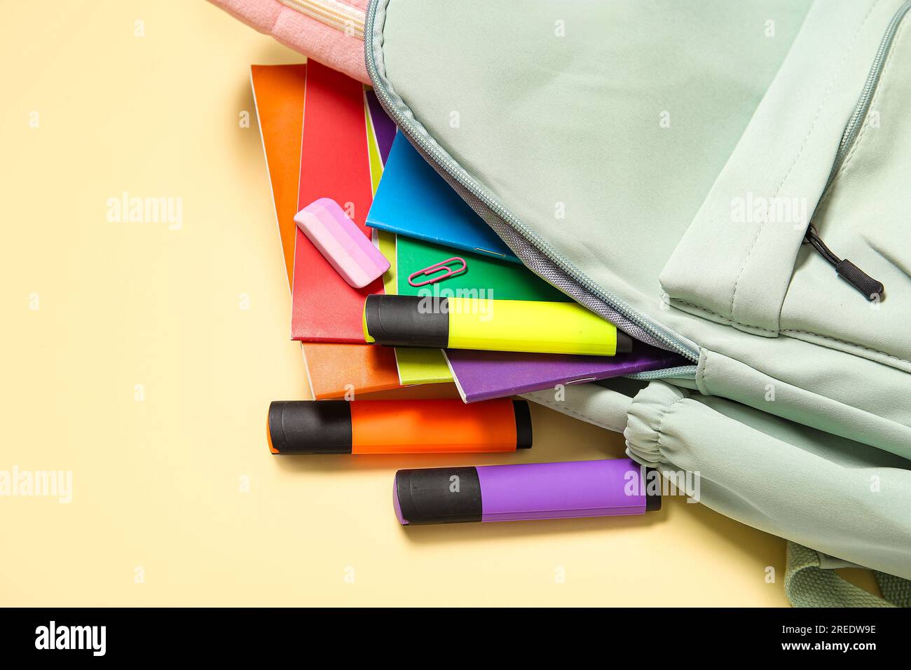 Green school backpack with different stationery on pale yellow background Stock Photo