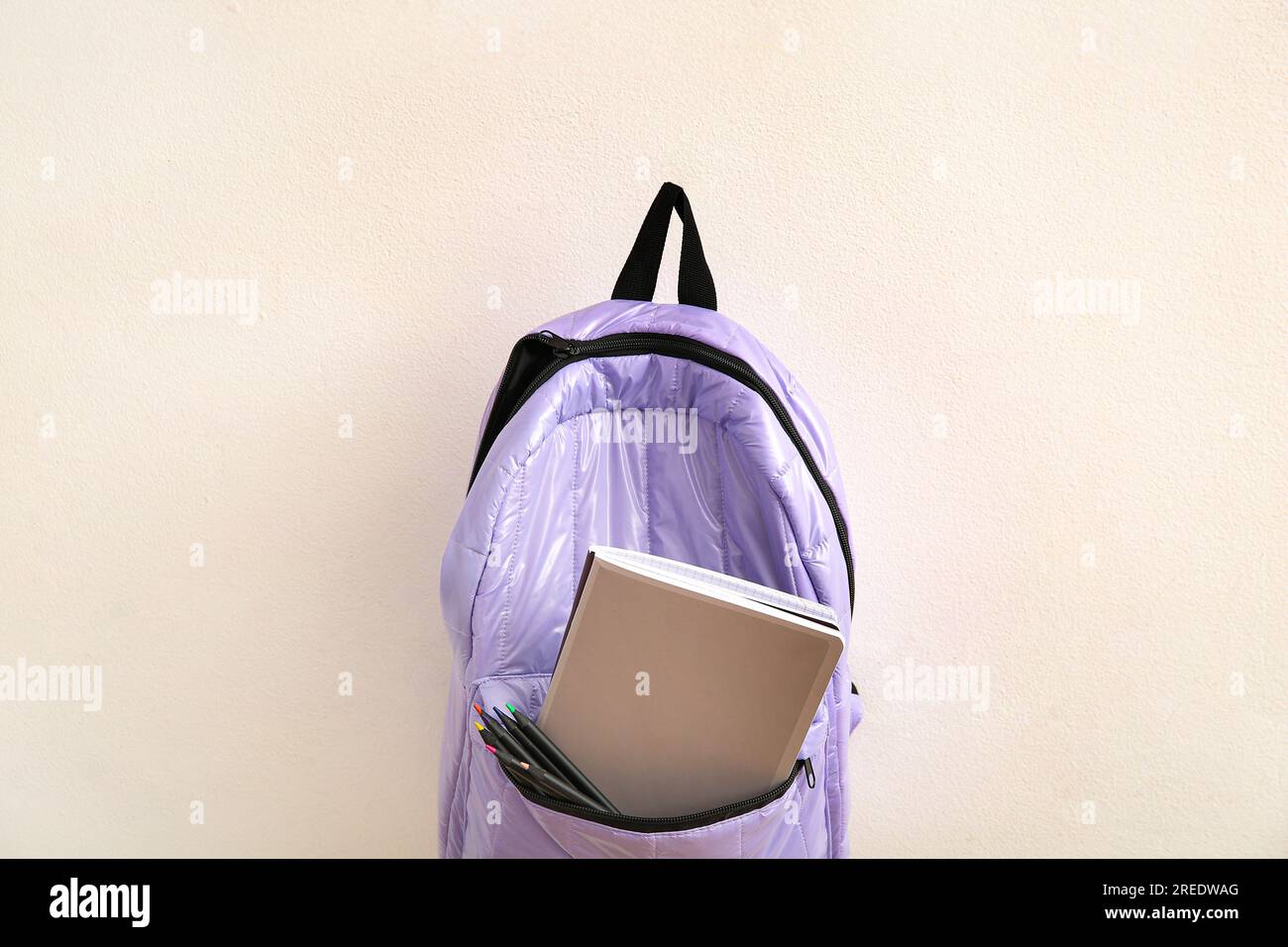 Lilac school backpack with stationery on light background Stock Photo