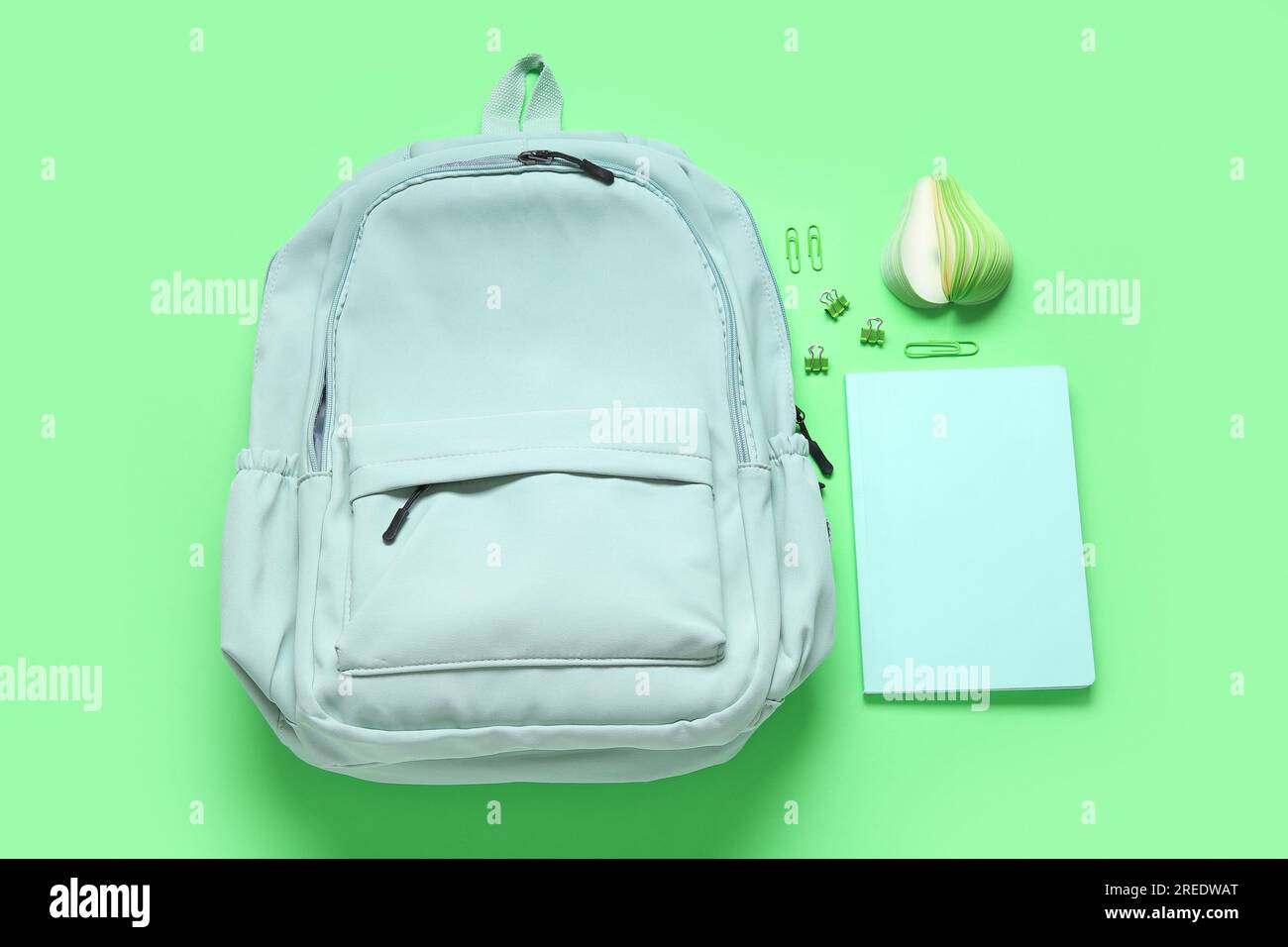 Stylish school backpack with different stationery on green background Stock Photo