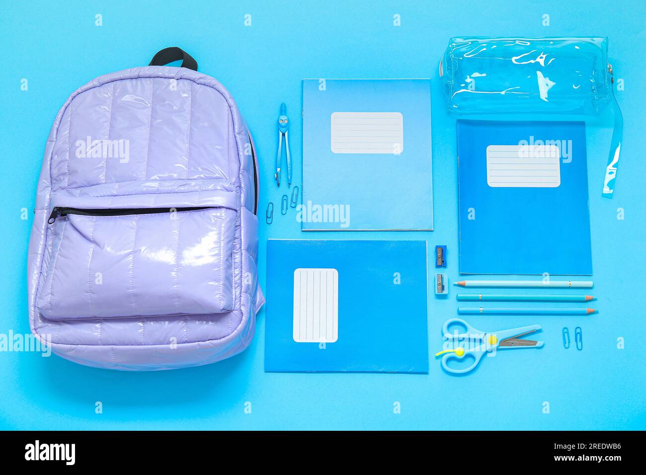 Lilac school backpack with stationery on blue background Stock Photo - Alamy