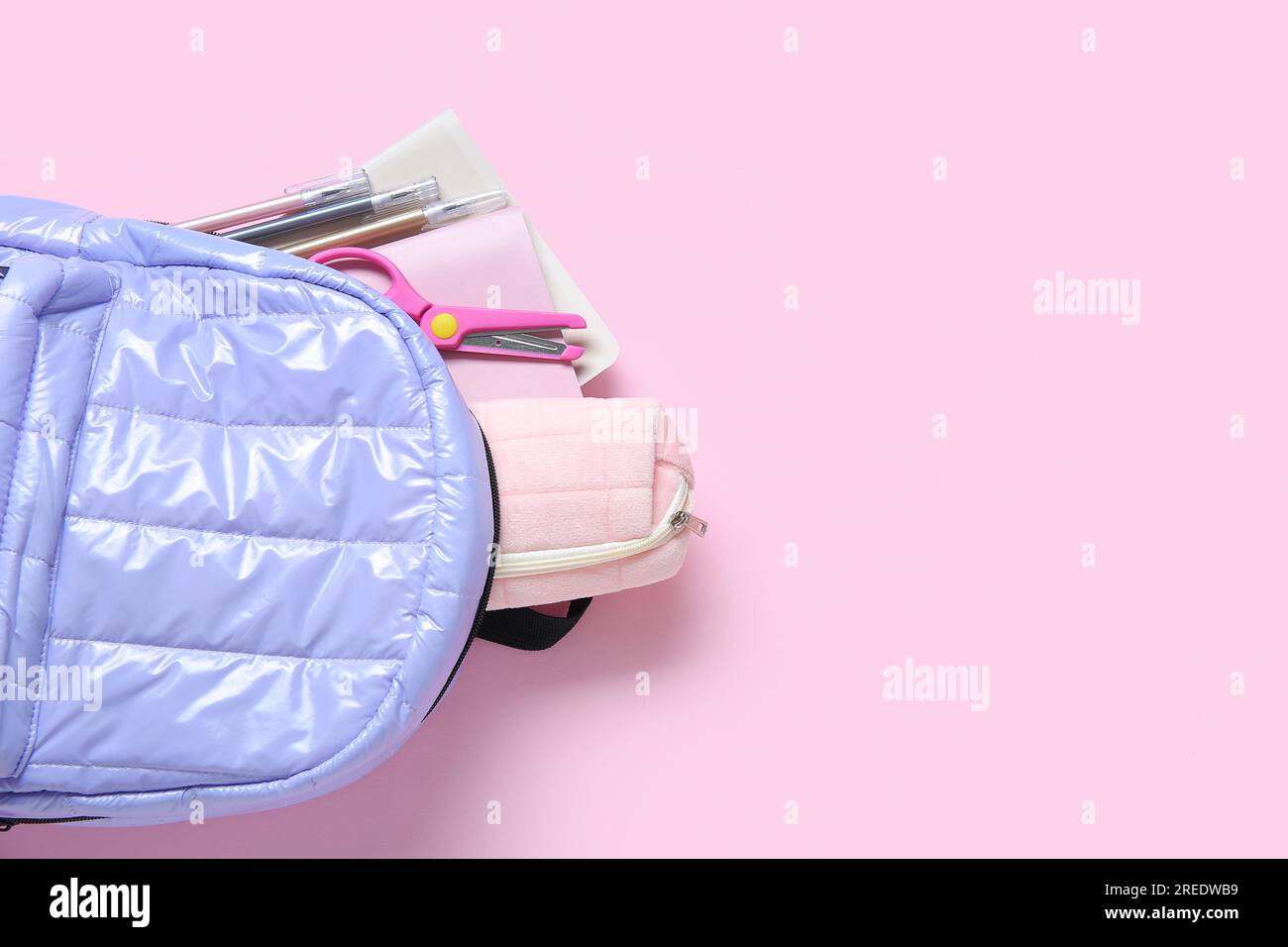 Lilac school backpack with stationery on pink background Stock Photo