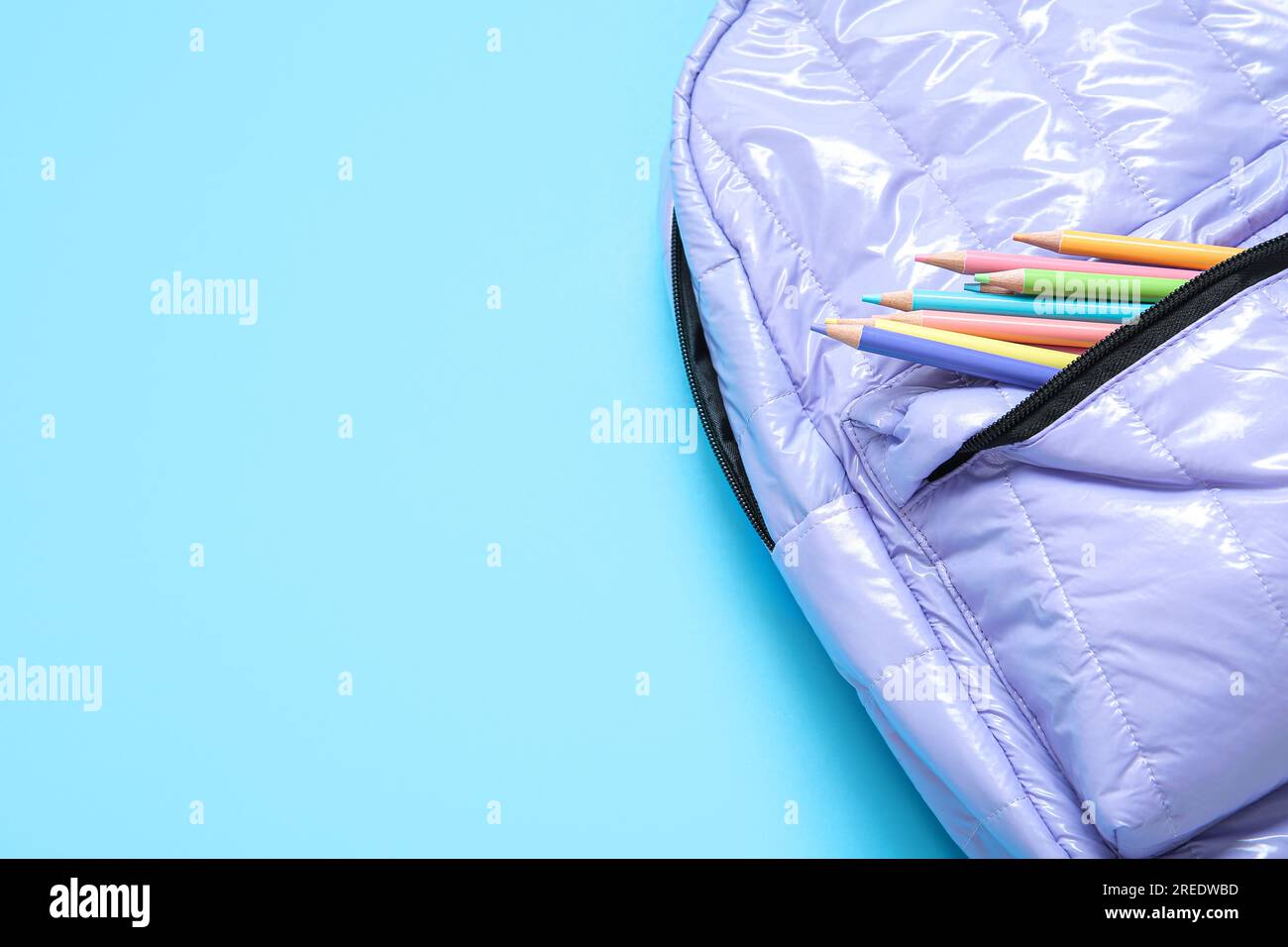 Lilac school backpack with stationery on blue background Stock Photo