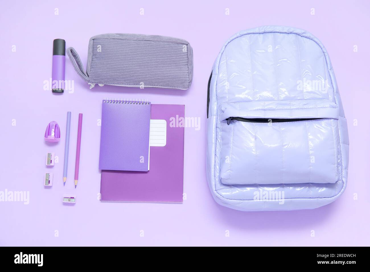 Lilac school backpack with different stationery on purple background Stock Photo