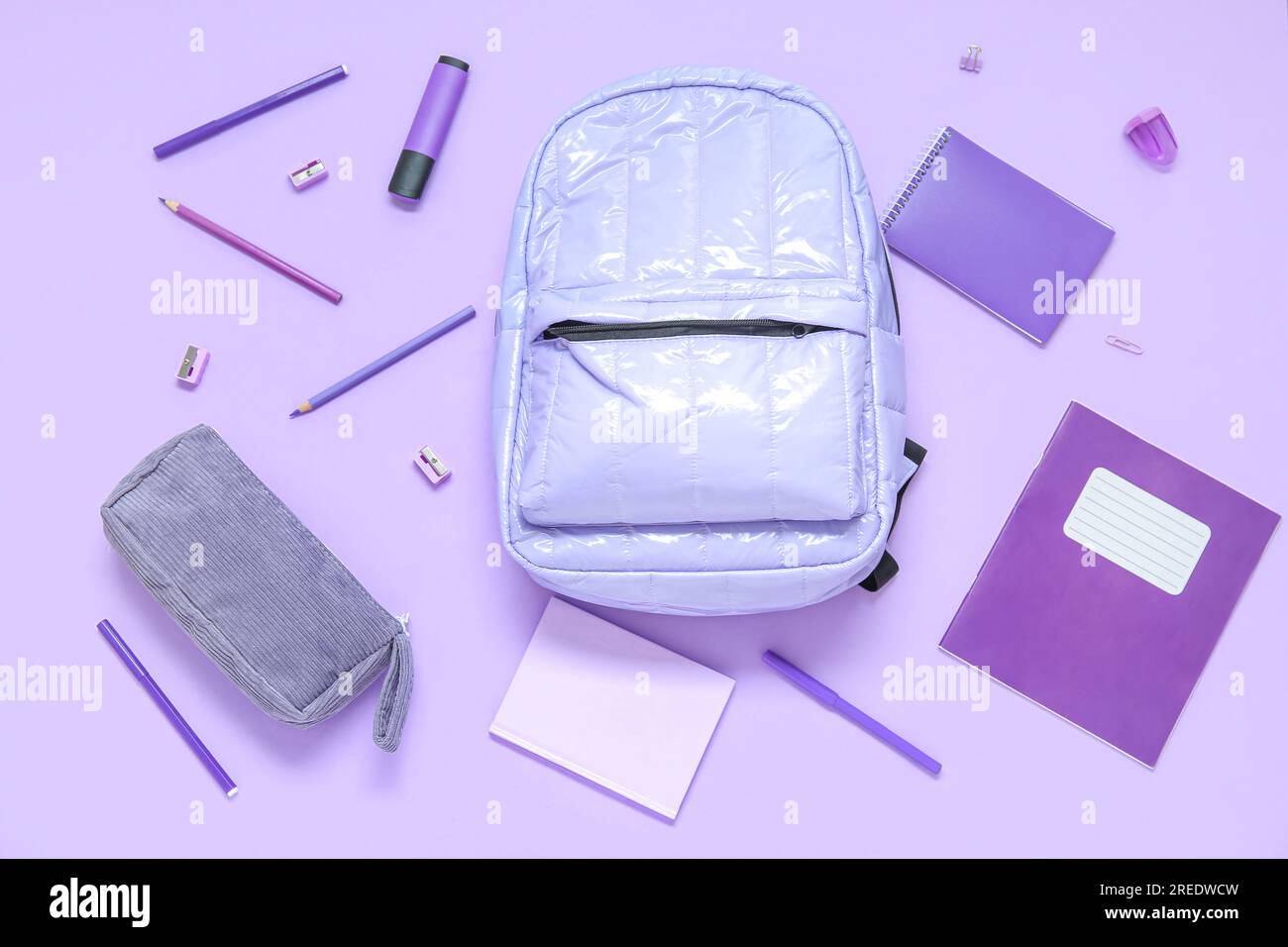 Lilac school backpack with different stationery on purple background Stock Photo