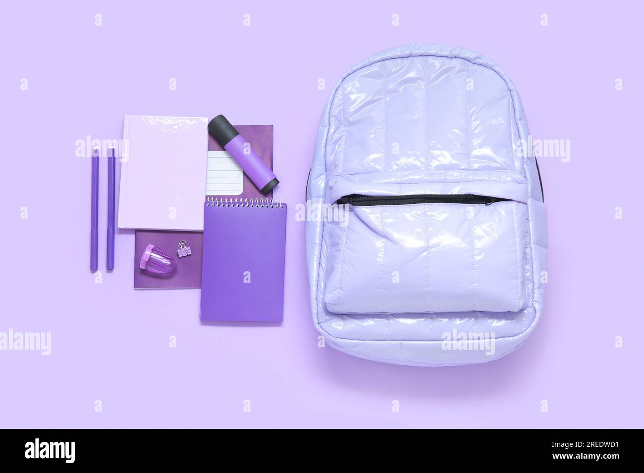 Lilac school backpack with different stationery on purple background Stock Photo