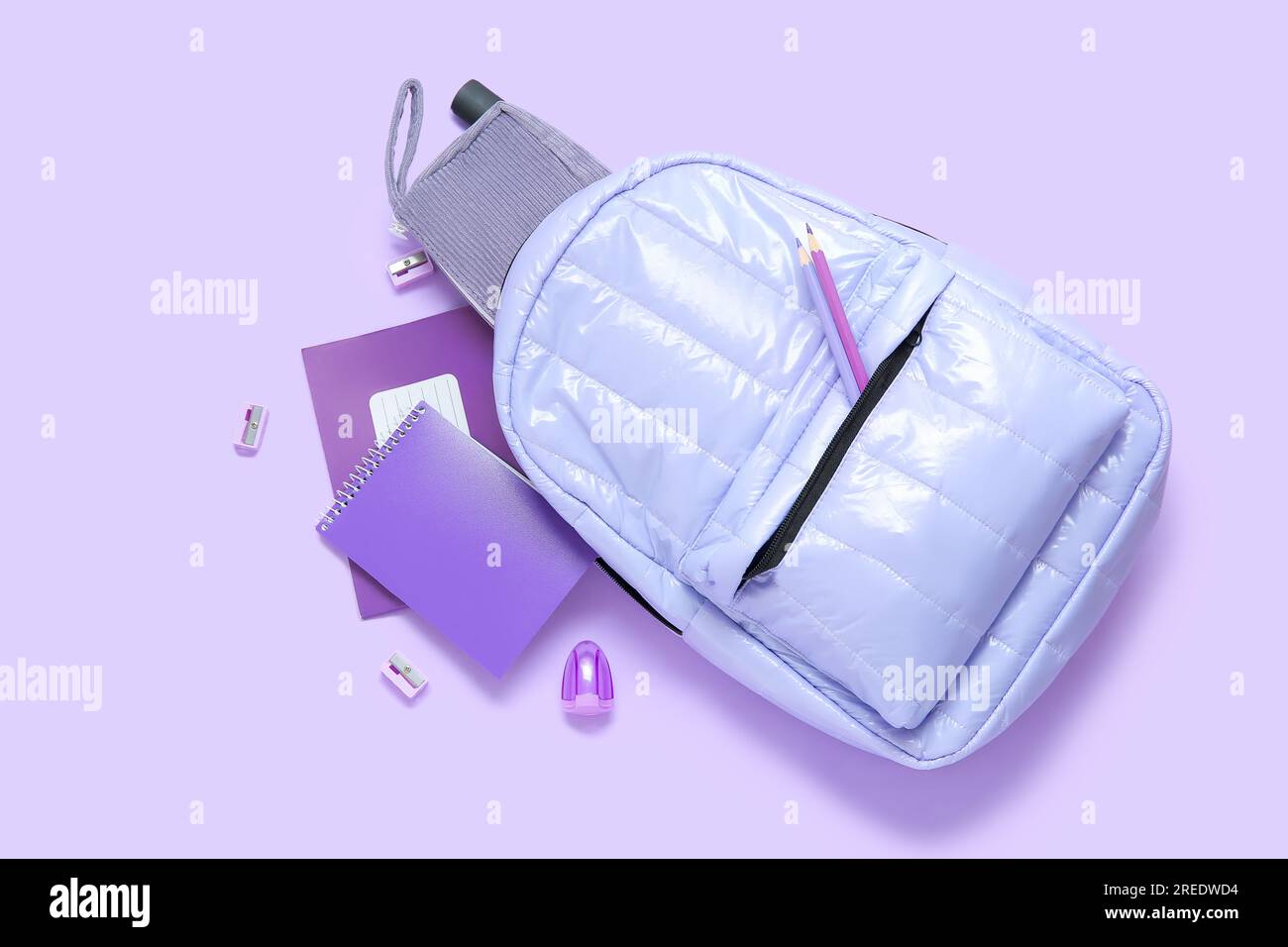 Lilac school backpack with different stationery on purple background Stock Photo
