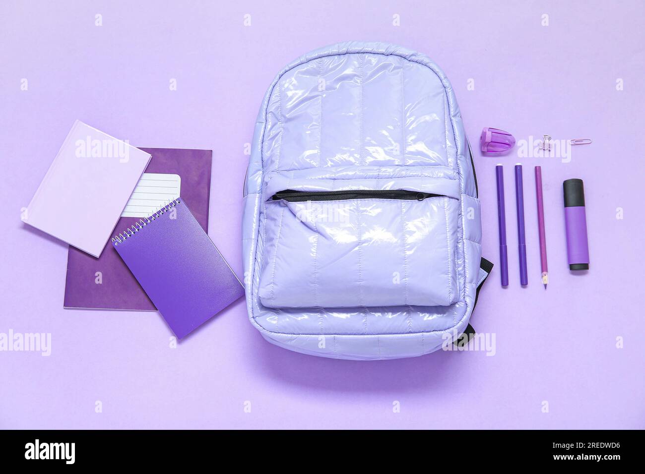 Lilac school backpack with different stationery on purple background Stock Photo