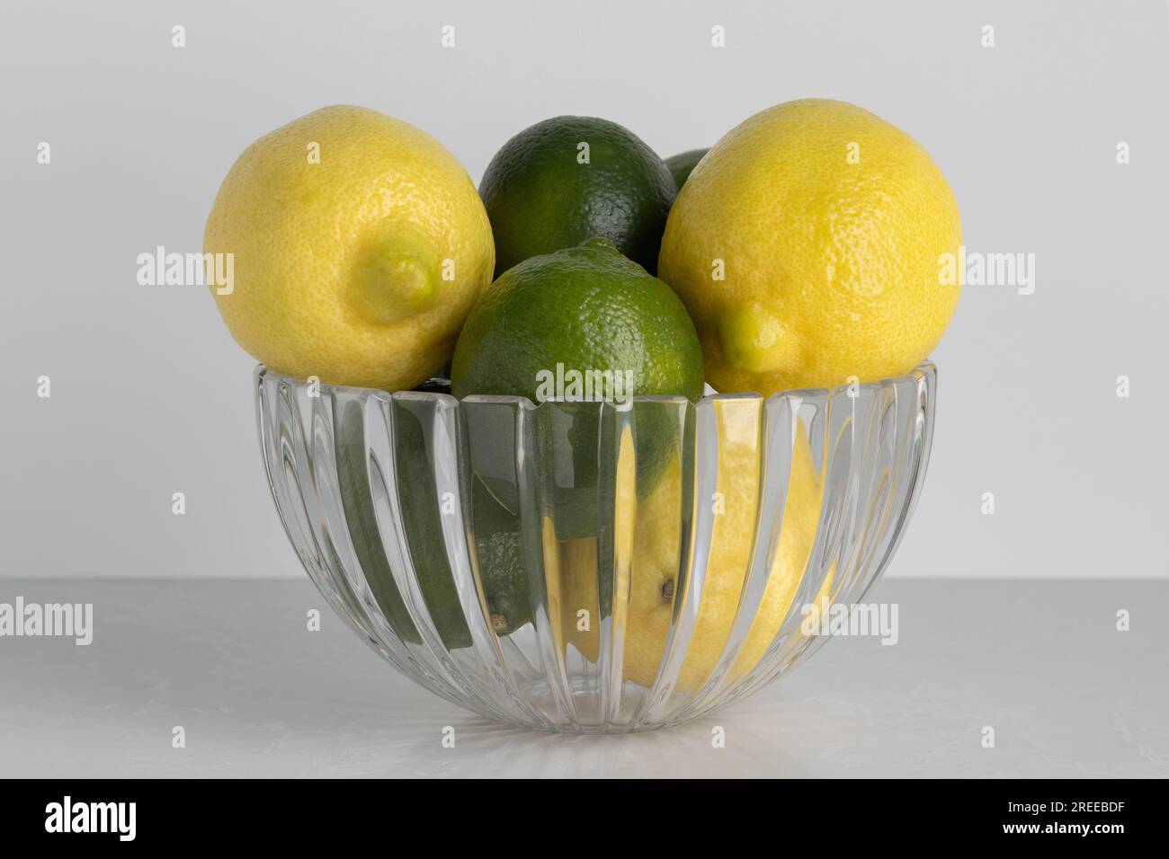 a beautiful cut crystal bowl filled with lemons and limes on a white background with copy space Stock Photo